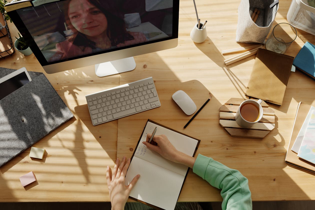 Person on a video call at their desk taking notes