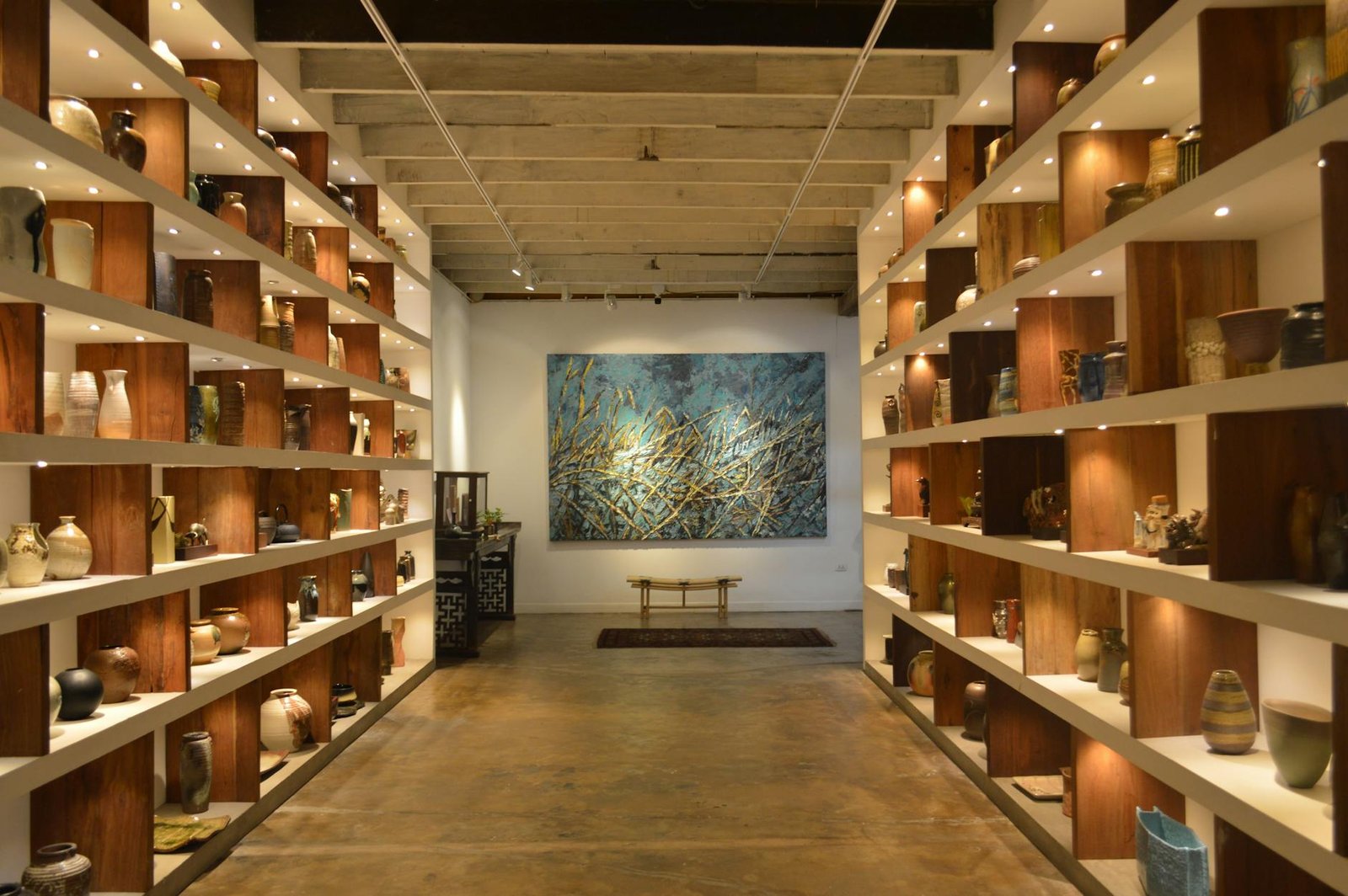 Gallery interior with natural wood shelving and warm lighting